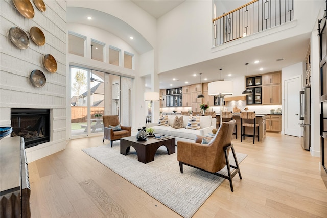 2217 Grey September St, Celina, TX 75009 - living room featuring light wood-style floors, a towering ceiling, a fireplace, and recessed lighting