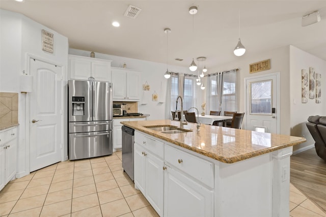 320 Grassland Dr, Denton, TX 76210 - kitchen featuring stainless steel appliances, light tile patterned floors, a center island with sink, white cabinetry, and light stone counters