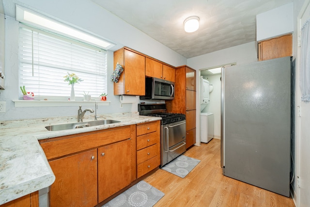 514 Fairview Dr, Richardson, TX 75081 - kitchen featuring appliances with stainless steel finishes, stacked washer / drying machine, light countertops, light wood finished floors, and brown cabinets