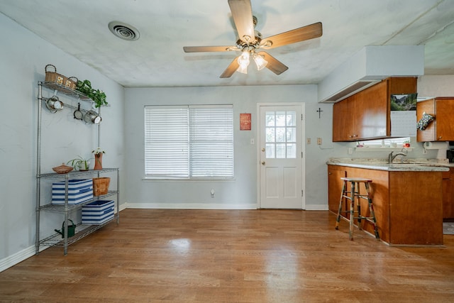 514 Fairview Dr, Richardson, TX 75081 - kitchen with brown cabinetry, light wood-style floors, a kitchen bar, a ceiling fan, and light countertops
