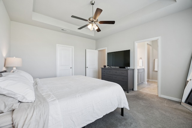 1001 Boulder Rd, Weatherford, TX 76085 - bedroom featuring a tray ceiling, light carpet, ensuite bath, and a ceiling fan