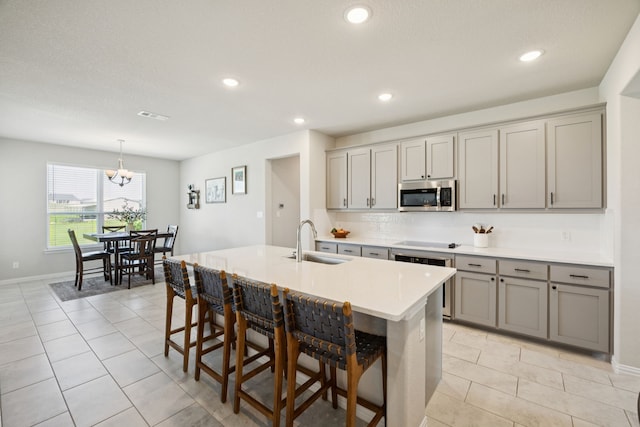 1001 Boulder Rd, Weatherford, TX 76085 - kitchen featuring stainless steel microwave, gray cabinetry, wall oven, black electric cooktop, and a kitchen breakfast bar