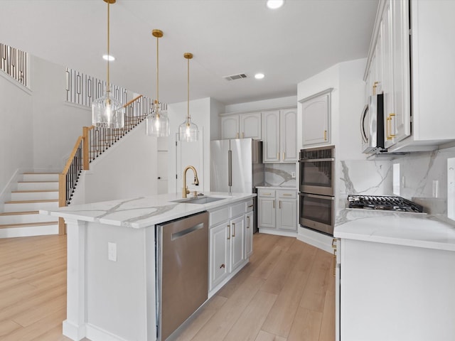 11342 Raveneaux Dr, Frisco, TX 75033 - kitchen with stainless steel appliances, light wood-style floors, tasteful backsplash, a center island with sink, and recessed lighting