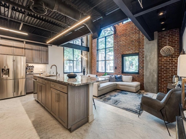 3110 Thomas Ave Unit 101, Dallas, TX 75204 - kitchen featuring appliances with stainless steel finishes, open floor plan, a towering ceiling, light stone countertops, and concrete floors