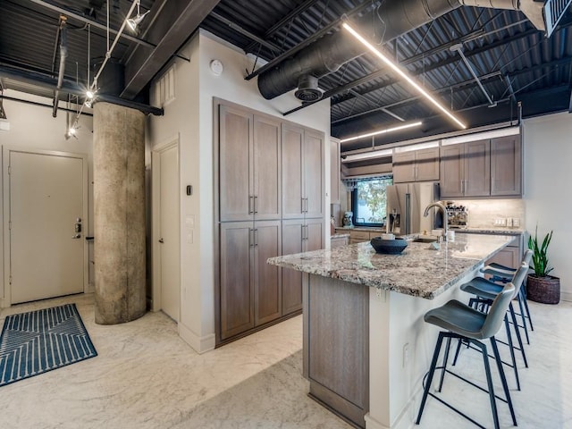 3110 Thomas Ave Unit 101, Dallas, TX 75204 - kitchen with stainless steel fridge with ice dispenser, light stone countertops, a kitchen bar, a center island with sink, and concrete flooring