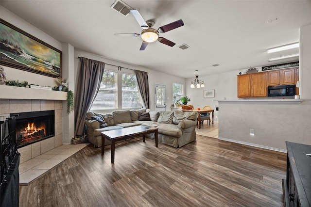 708 Hummingbird Trl, Crowley, TX 76036 - living room with wood finished floors, a ceiling fan, a tiled fireplace, and a chandelier