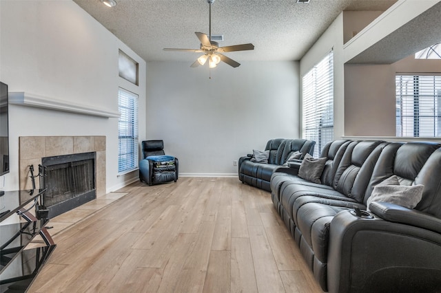 6720 Cedar Forest Trl, Dallas, TX 75236 - living area featuring a ceiling fan, light wood-style floors, healthy amount of natural light, a textured ceiling, and a tile fireplace