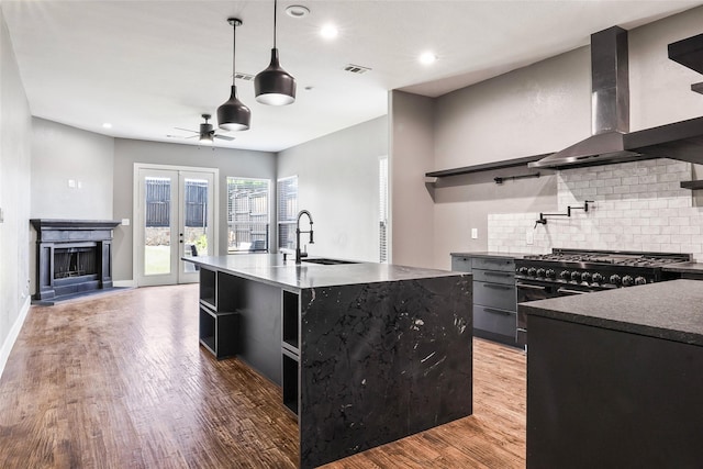 15321 Mount Evans Dr, Little Elm, TX 75068 - kitchen with wall chimney range hood, tasteful backsplash, light wood-style floors, ceiling fan, and a fireplace