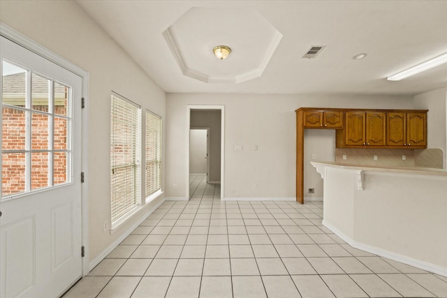 1036 E Oaklawn Dr, Talty, TX 75160 - kitchen featuring brown cabinetry, light countertops, a kitchen breakfast bar, a peninsula, and light tile patterned floors