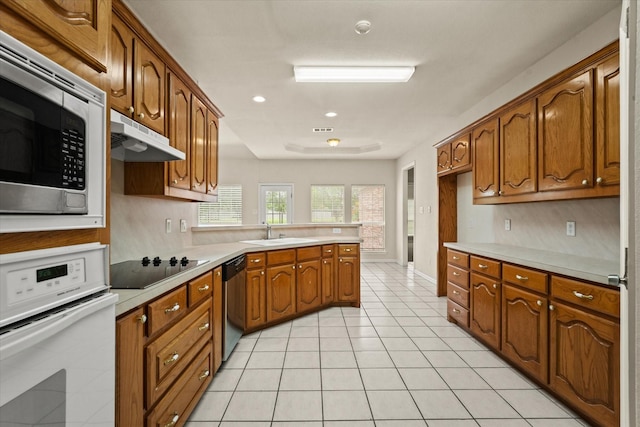 1036 E Oaklawn Dr, Talty, TX 75160 - kitchen with appliances with stainless steel finishes, a peninsula, brown cabinets, under cabinet range hood, and light countertops