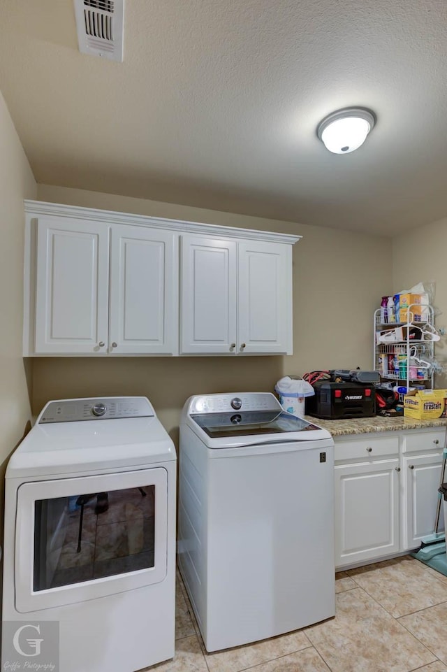 189 Bent Tree Loop, Haughton, LA 71037 - laundry area featuring washing machine and dryer, cabinet space, a textured ceiling, and light tile patterned floors