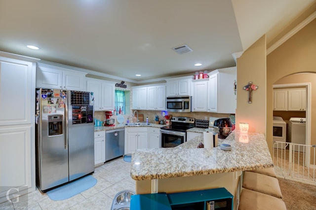 189 Bent Tree Loop, Haughton, LA 71037 - kitchen featuring appliances with stainless steel finishes, washing machine and dryer, a peninsula, light stone countertops, and white cabinetry