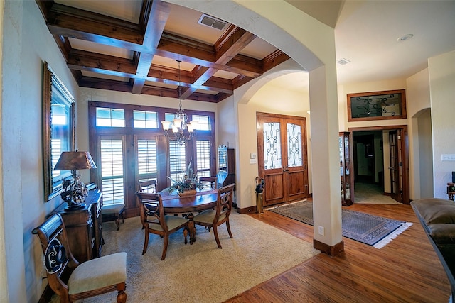 1702 High Point Dr, Pilot Point, TX 76258 - dining area with arched walkways, wood finished floors, a chandelier, beamed ceiling, and coffered ceiling