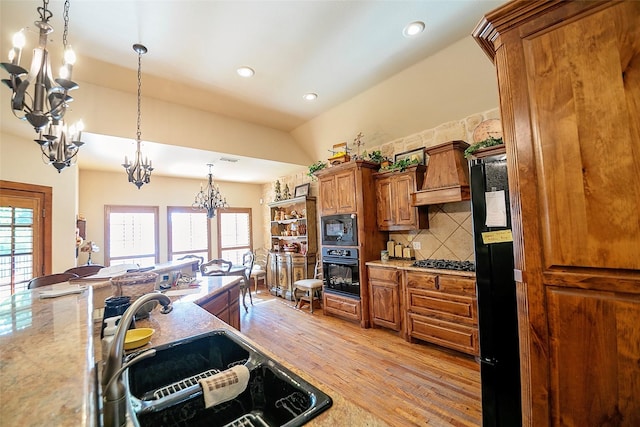 1702 High Point Dr, Pilot Point, TX 76258 - kitchen with black appliances, a chandelier, brown cabinets, light wood-style floors, and premium range hood
