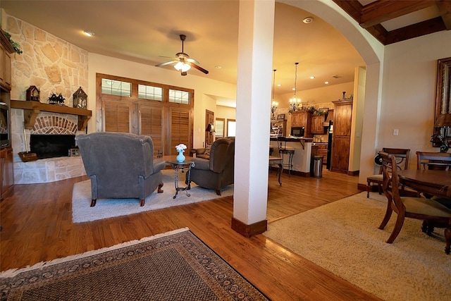 1702 High Point Dr, Pilot Point, TX 76258 - living area featuring a ceiling fan, a fireplace, wood finished floors, arched walkways, and a chandelier