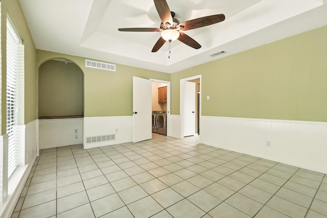 9901 Burnham Dr, Dallas, TX 75243 - unfurnished room with washer and dryer, a tray ceiling, a wainscoted wall, ceiling fan, and arched walkways