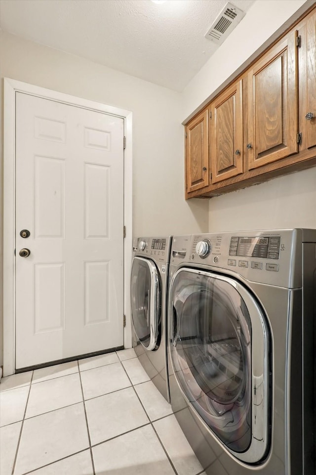 9901 Burnham Dr, Dallas, TX 75243 - laundry room with washing machine and clothes dryer, cabinet space, and light tile patterned floors