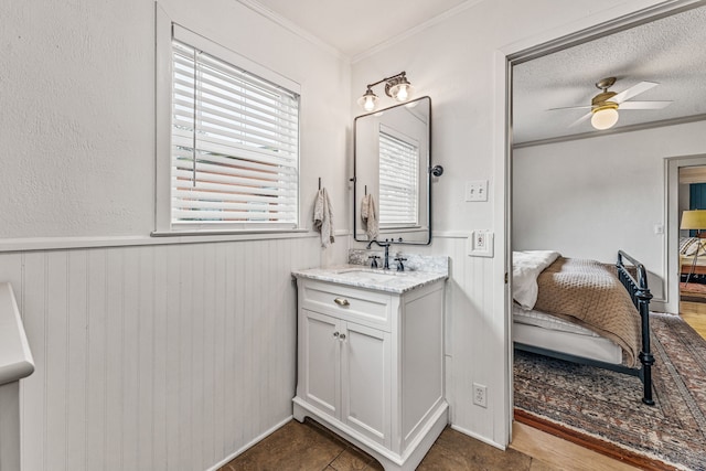887 N Clinton St, Stephenville, TX 76401 - bathroom with crown molding, ensuite bathroom, vanity, a wainscoted wall, and ceiling fan