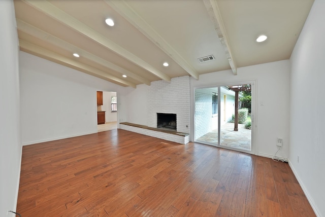 4949 Mill Run Rd, Dallas, TX 75244 - unfurnished living room featuring beamed ceiling, wood-type flooring, a brick fireplace, and recessed lighting