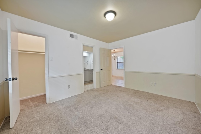 4949 Mill Run Rd, Dallas, TX 75244 - unfurnished bedroom with a walk in closet, carpet flooring, a chandelier, a closet, and connected bathroom
