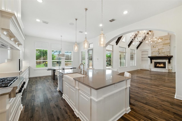 4510 Woodbine Ln, Prosper, TX 75078 - kitchen with custom range hood, appliances with stainless steel finishes, dark wood-style floors, arched walkways, and a center island with sink