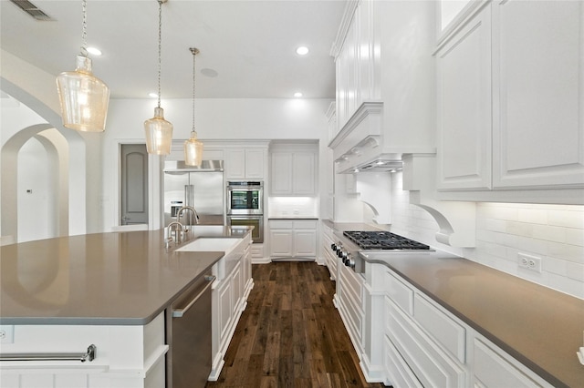 4510 Woodbine Ln, Prosper, TX 75078 - kitchen featuring appliances with stainless steel finishes, arched walkways, white cabinets, dark wood-style floors, and backsplash