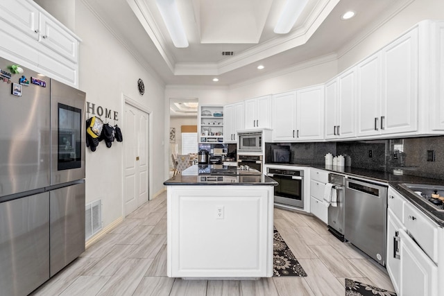200 Mill Xing W Unit W, Colleyville, TX 76034 - kitchen with stainless steel appliances, dark countertops, a center island, white cabinets, and ornamental molding
