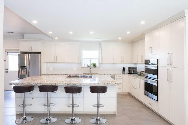 6956 Meadowbriar Ln, Dallas, TX 75230 - kitchen with appliances with stainless steel finishes, a center island, a kitchen breakfast bar, tasteful backsplash, and recessed lighting