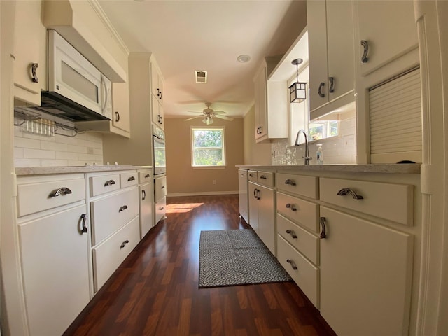 2225 Shady Brook Dr, Bedford, TX 76021 - kitchen with dark wood finished floors, ceiling fan, wall oven, light countertops, and white cabinets