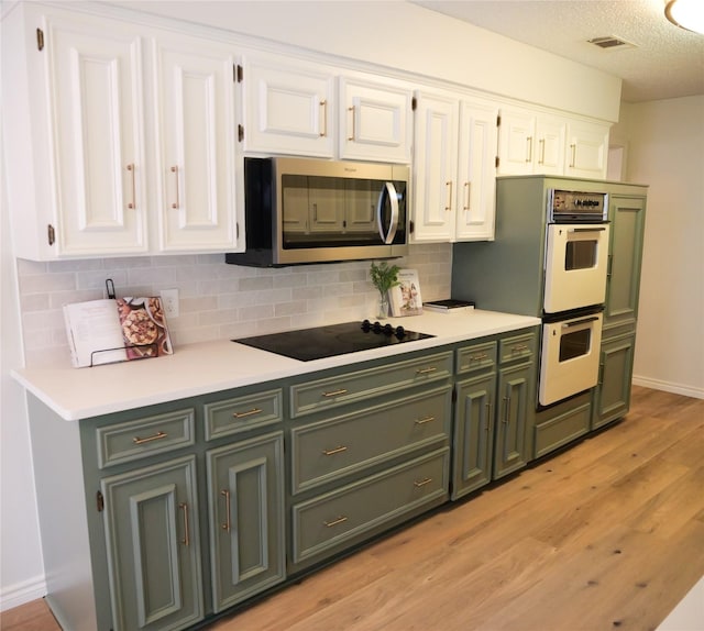 3501 Pecan Cir, Bedford, TX 76021 - kitchen with green cabinets, stainless steel microwave, white double oven, white cabinets, and a textured ceiling