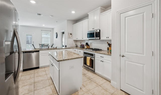 3814 Bastrop St, Melissa, TX 75454 - kitchen featuring stainless steel appliances, decorative backsplash, a center island, light stone countertops, and light tile patterned floors