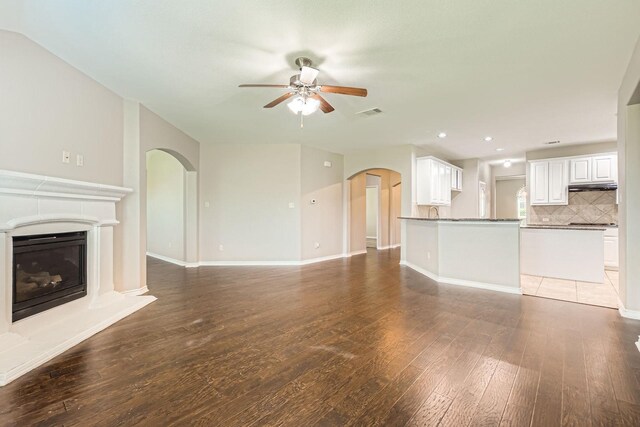 1119 Leafy Glade Rd, Forney, TX 75126 - unfurnished living room featuring arched walkways, ceiling fan, wood-type flooring, a glass covered fireplace, and recessed lighting