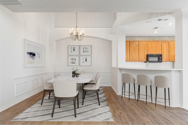 511 Poplar Ln, Irving, TX 75063 - dining room featuring a chandelier, light wood-style floors, a decorative wall, and wainscoting