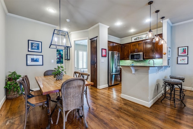 7333 Valley View Ln Unit 304, Dallas, TX 75240 - kitchen with stainless steel appliances, a breakfast bar, dark wood-style flooring, crown molding, and recessed lighting