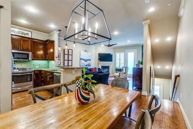 7333 Valley View Ln Unit 304, Dallas, TX 75240 - dining room with wood finished floors, a fireplace, recessed lighting, and crown molding