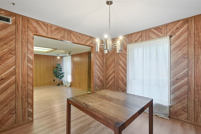 921 Sleepy Hollow Dr, Garland, TX 75043 - dining space with wooden walls, light wood-style flooring, and a chandelier