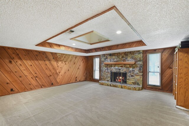 921 Sleepy Hollow Dr, Garland, TX 75043 - unfurnished living room with a textured ceiling, healthy amount of natural light, wood walls, a stone fireplace, and carpet