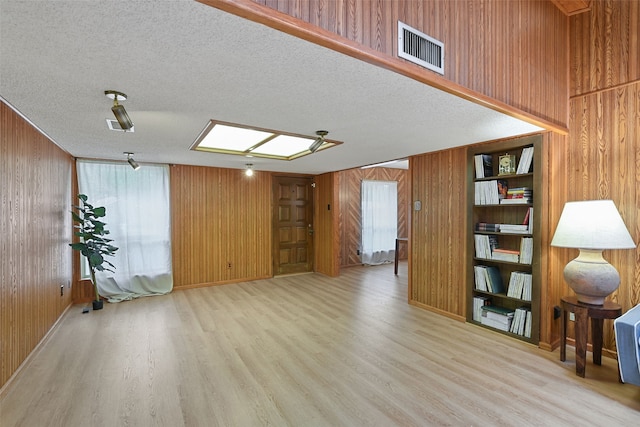 921 Sleepy Hollow Dr, Garland, TX 75043 - unfurnished living room featuring wood walls, wood finished floors, and a textured ceiling