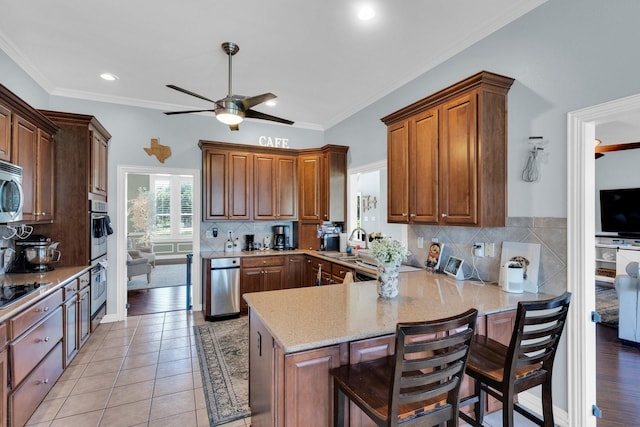 7251 Misty Glen Ln, Midlothian, TX 76065 - kitchen with a ceiling fan, a peninsula, appliances with stainless steel finishes, light stone counters, and recessed lighting