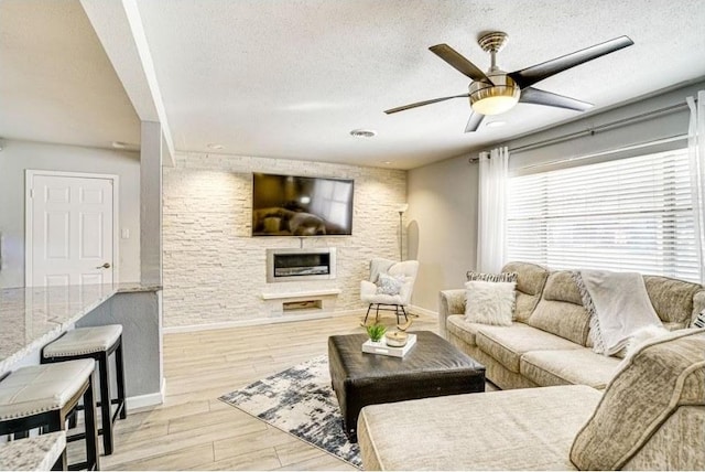 1037 Cavender Dr, Hurst, TX 76053 - living area featuring a ceiling fan, a textured ceiling, a large fireplace, and light wood-style flooring