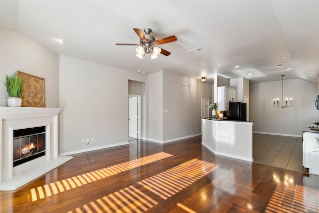 8648 Marion Dr, Frisco, TX 75036 - unfurnished living room with lofted ceiling, a ceiling fan, a chandelier, dark wood-style floors, and a glass covered fireplace