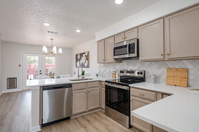 2508 Independence Dr, Mesquite, TX 75150 - kitchen with stainless steel appliances, a peninsula, a textured ceiling, light wood finished floors, and a chandelier