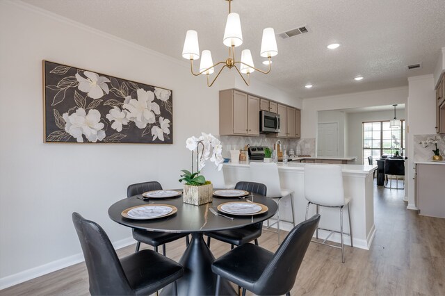 2508 Independence Dr, Mesquite, TX 75150 - dining area with a chandelier, light wood-style flooring, a textured ceiling, crown molding, and recessed lighting
