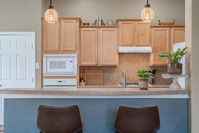 134 Fox Hollow Blvd, Forney, TX 75126 - kitchen with white microwave, light brown cabinetry, under cabinet range hood, and range
