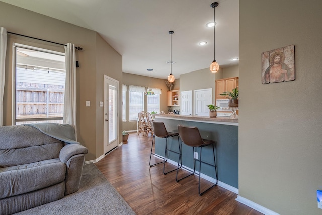 134 Fox Hollow Blvd, Forney, TX 75126 - kitchen featuring dark wood-style floors, a kitchen breakfast bar, white microwave, light brown cabinets, and open floor plan