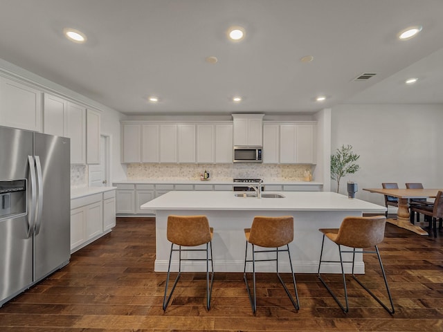 1701 Briar Hill Dr, Denton, TX 76207 - kitchen featuring appliances with stainless steel finishes, dark wood-style floors, a kitchen breakfast bar, backsplash, and recessed lighting