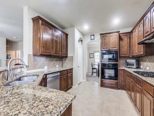 1314 Merrimac Dr, Allen, TX 75002 - kitchen with black appliances, light stone counters, arched walkways, decorative backsplash, and light tile patterned floors
