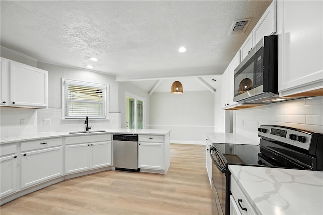 3505 Scott Dr, Rowlett, TX 75088 - kitchen with appliances with stainless steel finishes, a textured ceiling, light wood finished floors, white cabinetry, and vaulted ceiling