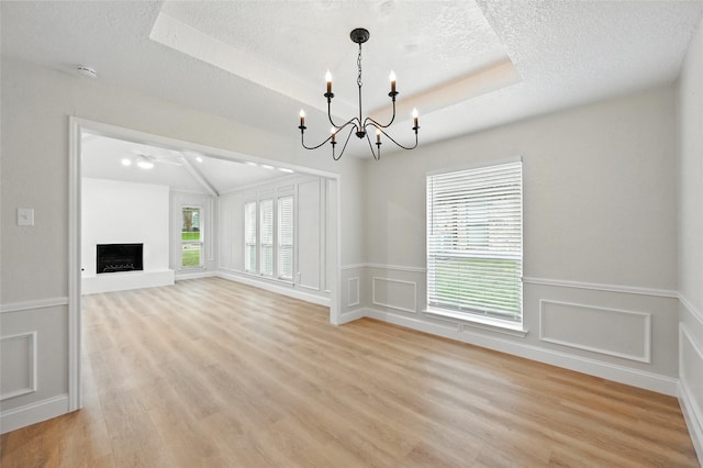 3505 Scott Dr, Rowlett, TX 75088 - unfurnished living room with a chandelier, light wood-style flooring, a fireplace with raised hearth, a textured ceiling, and a decorative wall