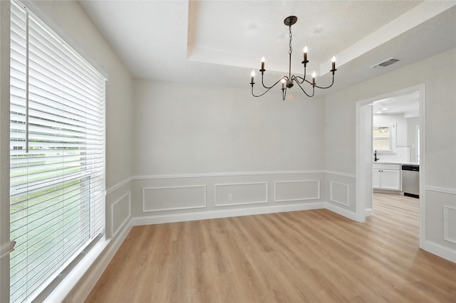 3505 Scott Dr, Rowlett, TX 75088 - empty room with a chandelier, a tray ceiling, light wood-type flooring, wainscoting, and a decorative wall